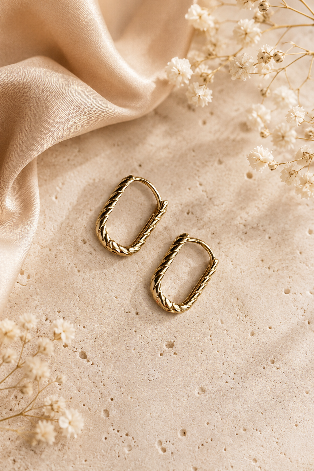 18k auksu dengti susukto dizaino ovalūs auskarai šviesiame fone